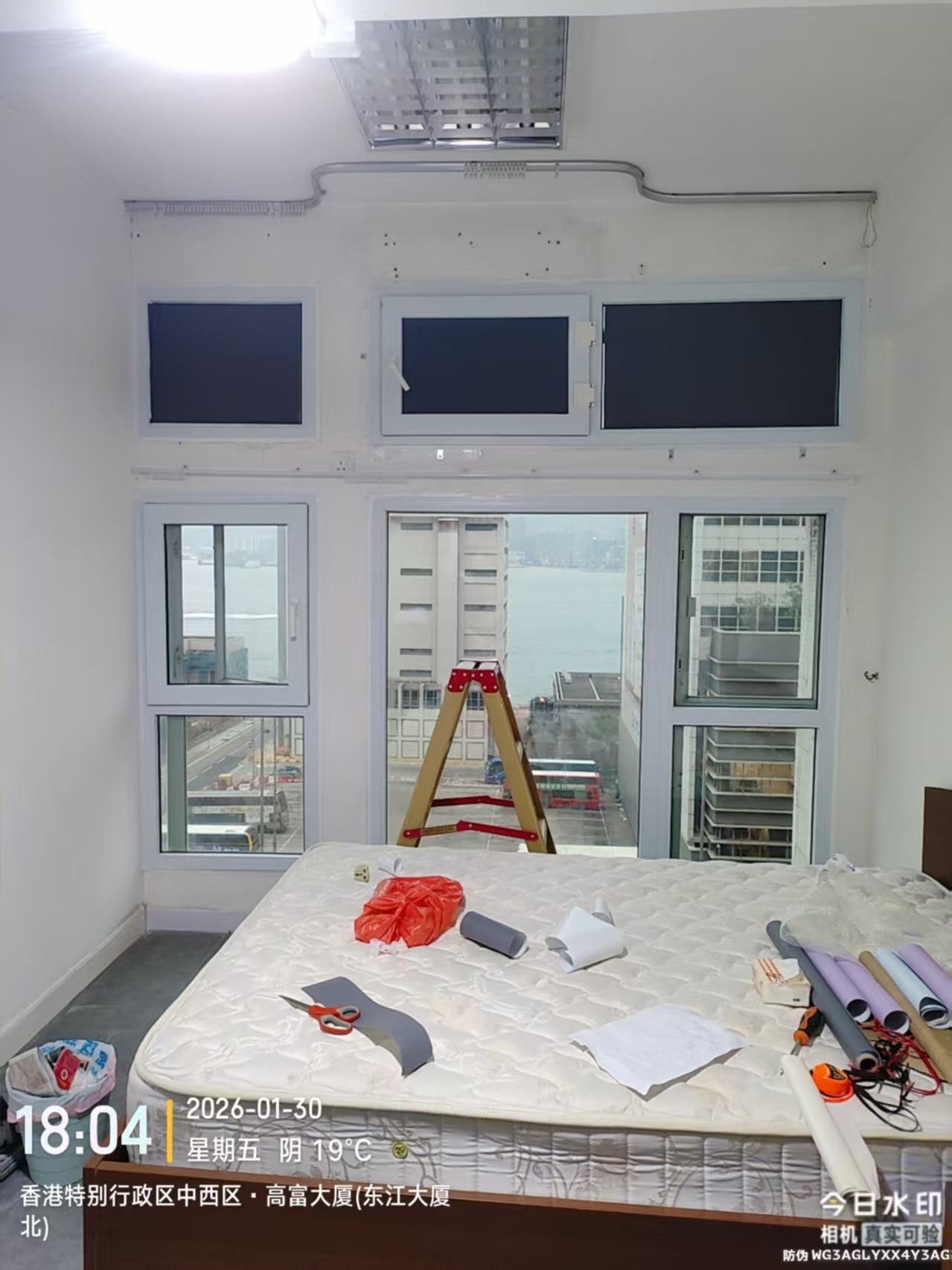 An interior window assembly with installation supplies in the room, overlooking a road and water.